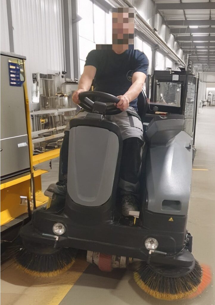 Agent France Clean Group sur une balayeuse autoportée dans une usine